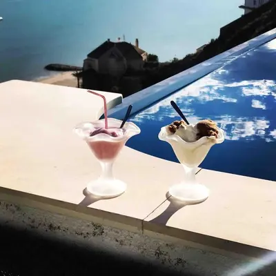 two glasses of ice cream on a ledge next to a pool at Villa conectada al mediterraneo, Infinity pool in Faro de Cullera