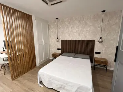 a bedroom with a white bed and a wooden headboard at Loft en puerto de Valencia in Valencia