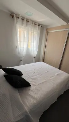 a white bed with black pillows in a bedroom at Apartment near the beach in Valencia