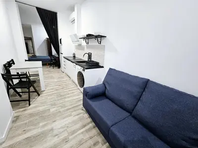 a living room with a blue couch and a kitchen at Apart Valencia A in Valencia