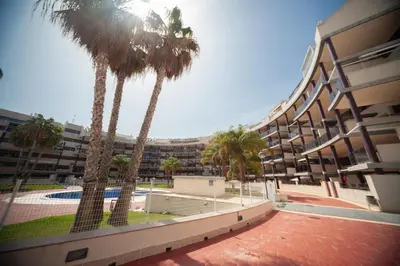 a building with palm trees in front of a building at Fantástico apartamento con todos los servicios in Canet de Berenguer