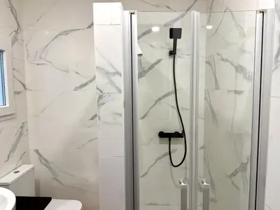 a shower in a bathroom with white marble at Reinapart Cabanyal in Valencia