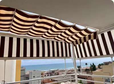 a black and white umbrella on a balcony with the beach at Lugar junto al mar in Casas Las Basas