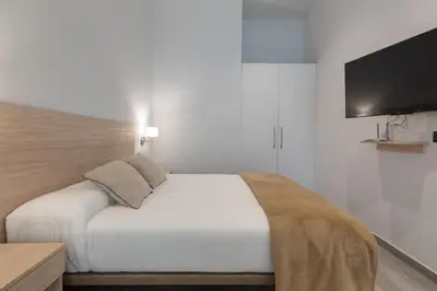 a bedroom with a bed with a tv on the wall at Apartamento 1º nuevo cerca playa in Valencia