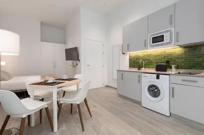 a kitchen and living room with a table and a washing machine at Apartamento 1º nuevo cerca playa in Valencia