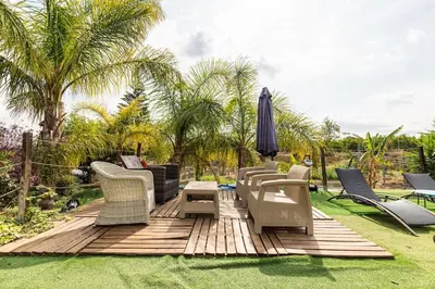 a deck with chairs and an umbrella on the grass at Les moreres a space for tranquility in Valencia