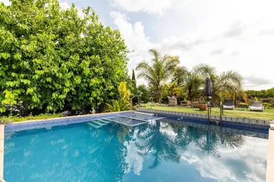 a swimming pool with two chairs and trees at Les moreres a space for tranquility in Valencia