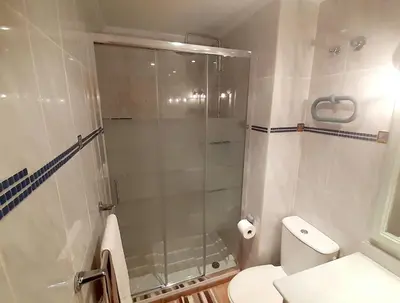 a bathroom with a toilet and a glass shower at Charming apt by the beach with stunning harbor views in Port Saplaya