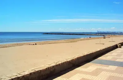 a sandy beach with a pier in the background at Charming apt by the beach with stunning harbor views in Port Saplaya