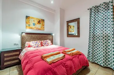 a bedroom with a bed with a red blanket at Charming apt by the beach with stunning harbor views in Port Saplaya