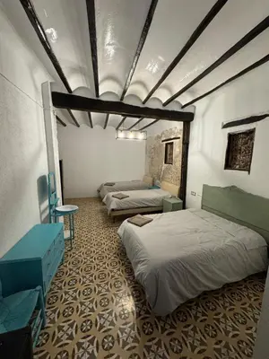 a room with three beds and a table and chairs at La Replaceta in Segorbe