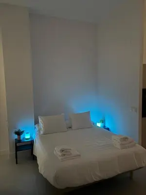 a bedroom with a white bed with a blue light at Centric Loft near Arts & Science in Valencia