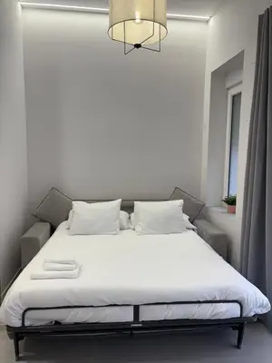 a bed with white sheets and pillows in a room at Centric Loft near Arts & Science in Valencia