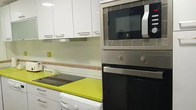 a kitchen with white cabinets and a black microwave at Cisne! Vistas al mar, piscina y garaje in Cullera