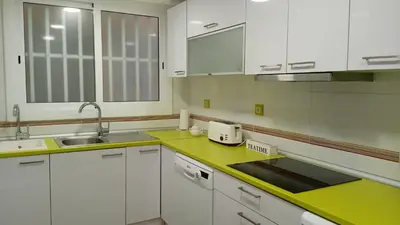 a kitchen with white cabinets and green counter tops at Cisne! Vistas al mar, piscina y garaje in Cullera
