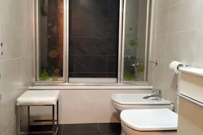 a bathroom with a toilet and a sink and a window at Cisne! Vistas al mar, piscina y garaje in Cullera