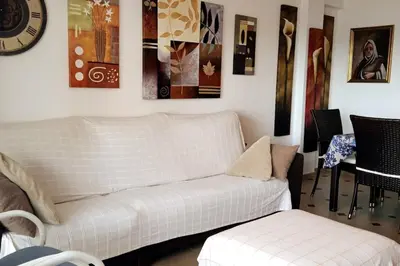 a living room with a white couch and a clock at Cisne! Vistas al mar, piscina y garaje in Cullera