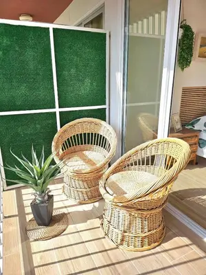 three wicker chairs and a potted plant on a porch at Coqueto apartamento en la playa in Puebla de Farnals