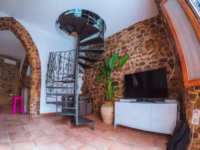 a living room with a tv and a stone wall at Casa de piedra en el casco antiguo de Sagunto in Sagunto