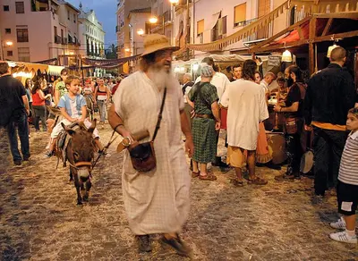 a man walking down a street with a cow in a market at Casa de piedra en el casco antiguo de Sagunto in Sagunto