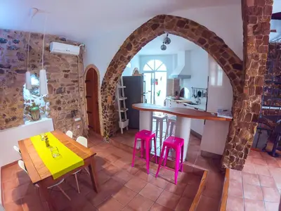 a kitchen with a table and some pink stools at Casa de piedra en el casco antiguo de Sagunto in Sagunto