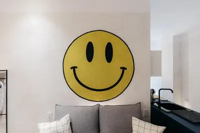 a yellow smiley face on a wall above a bed at Trendy Retreat in Valencia in Valencia