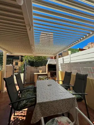 a table and chairs under awning on a patio at Casa con Barbacoa en Urbanización Privada in Valencia