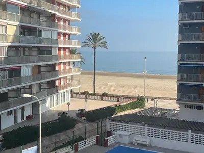 a building next to a beach with a palm tree at Paradise Cullera in Cullera