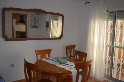 a dining room table with a mirror and a table and chairs at Arbocer playa Puçol in Puzol
