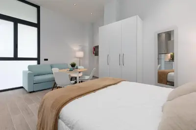 a white bedroom with a bed and a table at Apartamento 2º nuevo 400 mt al mar in Valencia