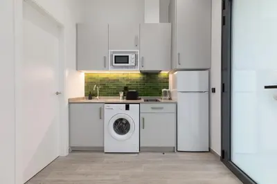 a kitchen with white cabinets and a washer and dryer at Apartamento 2º nuevo 400 mt al mar in Valencia