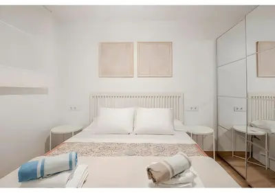 a white bedroom with a bed and two chairs at El Retiro - Frontal al mar, 1a Línea, como en tu casa in Cullera