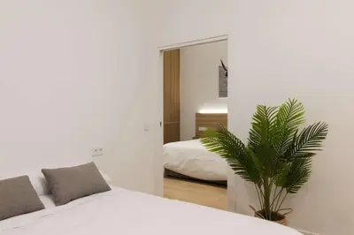 a bedroom with a white bed and a palm tree at Luxury Apartment Oceanografic 6 pax in Valencia