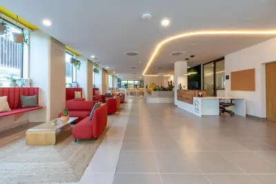 a lobby of a hospital with red chairs and tables at NIDO Malvarrosa Hotel - Apartamento in Valencia