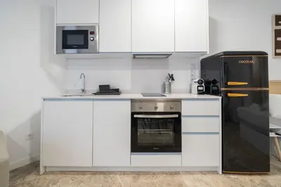 a kitchen with white cabinets and a black refrigerator at VLC Host - Tamarit in Valencia