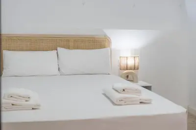 a bed with white sheets and pillows and a lamp at VLC Host - Tamarit in Valencia