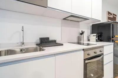 a white kitchen with a sink and a stove at VLC Host - Tamarit in Valencia