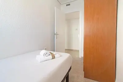 a bedroom with a white bed and a wooden door at Global Vacacional, Apartamento en primera linea de playa en Canet de Berenguer in Canet de Berenguer