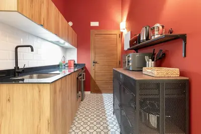 a kitchen with red walls and a sink and a counter at The Little Village Apartments in Valencia