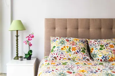 a bed with floral pillows and a lamp on a table at Cozy Suite next to Plaza del Ayuntamiento in Valencia