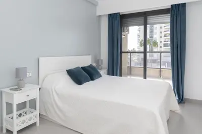a white bedroom with a white bed and a window at Espacio-1, 2-H in Cullera