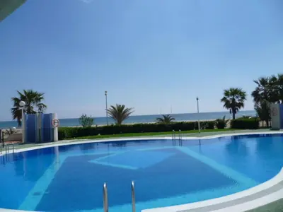 a large blue swimming pool with the ocean in the background at Espacio-1, 2-H in Cullera