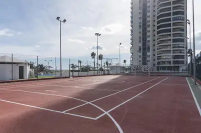 an empty tennis court in front of a building at Espacio-1, 2-H in Cullera