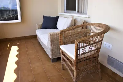 a living room with a wicker chair and a couch at Vacansis Apartamento Florazar 2, 4 in Cullera
