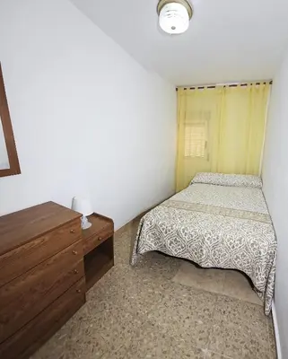 a small bedroom with a bed and a dresser at Vacansis Apartamento Cullera Mar in Cullera
