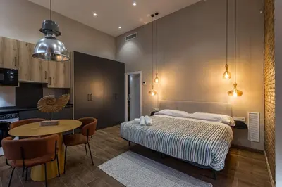 a bedroom with a bed and a table and a kitchen at Suite Premium junto al Río Turia 1 in Valencia