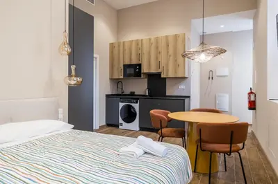 a bedroom with a bed and a table and a kitchen at Suite Premium junto al Río Turia 2 in Valencia