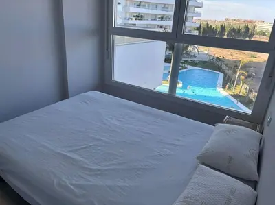 a bedroom with a bed and a window with a swimming pool at Appartement avec vue piscine in Canet de Berenguer