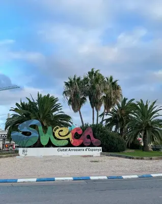 a sign in front of a street with palm trees at Valencia Apartamento Sol de Naranja in Sueca