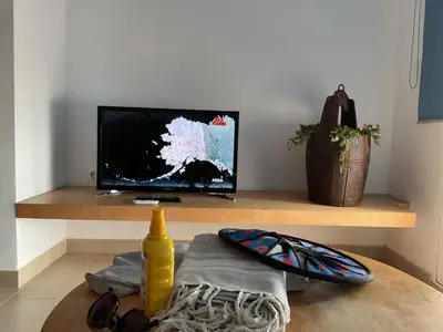 a living room with a television and a table at La Calita del Versalles in Faro de Cullera